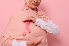 Ansicht einer muslimischen Frau mit Hijab mit rosaner Brustkrebs-Schleife auf Brusthöhe ©Taras Grebinets/Shutterstock.com